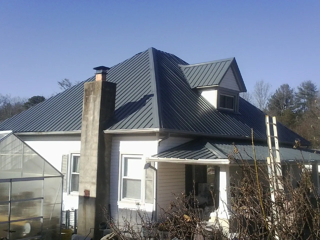 Dark blue standing seam metal roof on a white farmhouse with dormer — Slate & Tile Roof Repair by Roofing Brothers in Nyack
