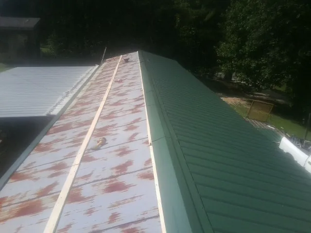 Old rusted panels beside newly installed green metal roofing — Wind Damage Roof Repair by Roofing Brothers in Nyack