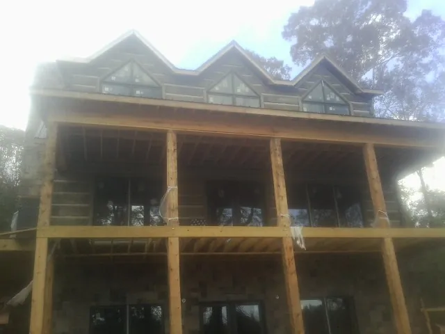 Dormers and porch framing on a large log home under construction — Roof Coating work by our crew in Nyack