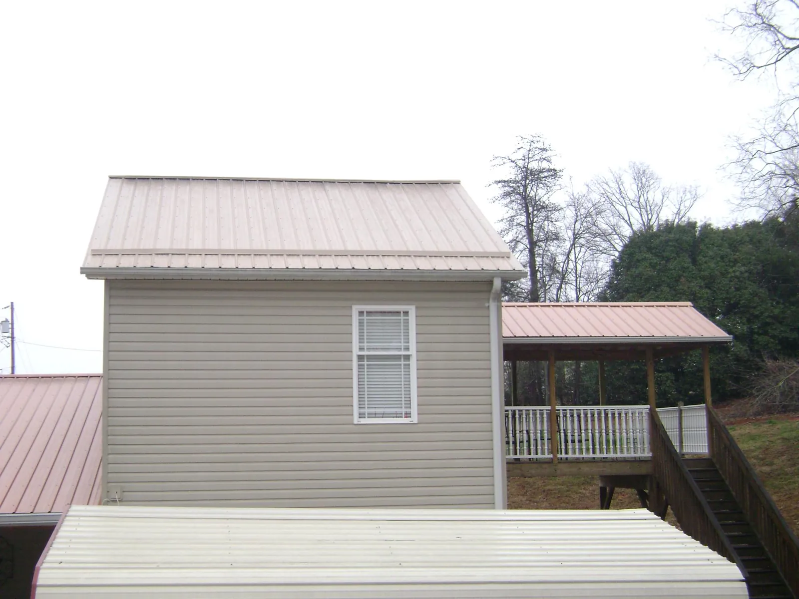 Tan metal roofs on a two story addition and attached porch, from a Roof Replacement job in Nyack