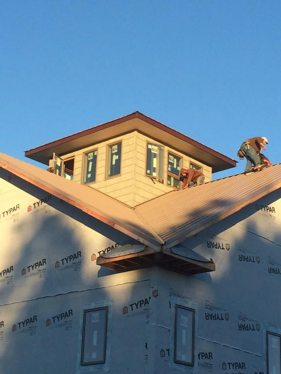 Roofers working around a rooftop cupola on a new metal roof at sunset — Roof Waterproofing in Nyack by Roofing Brothers